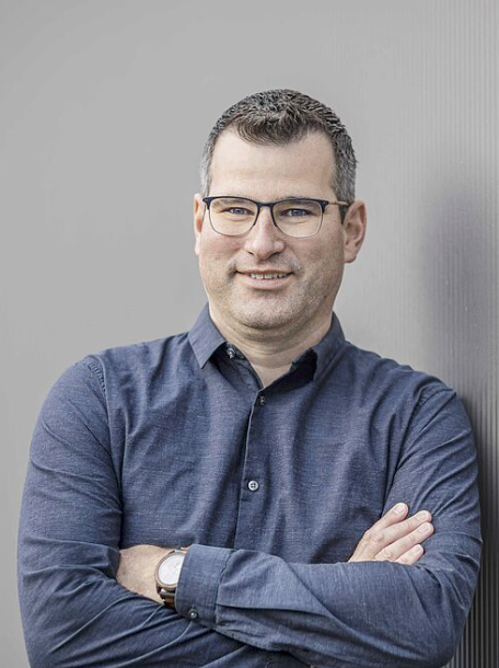 Mann mit verschränkten Armen, nachdenklich.