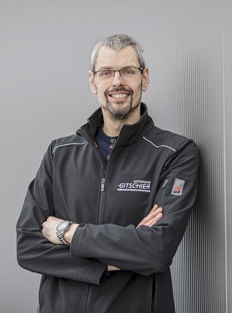 Mann in schwarzer Jacke, verschränkte Arme.