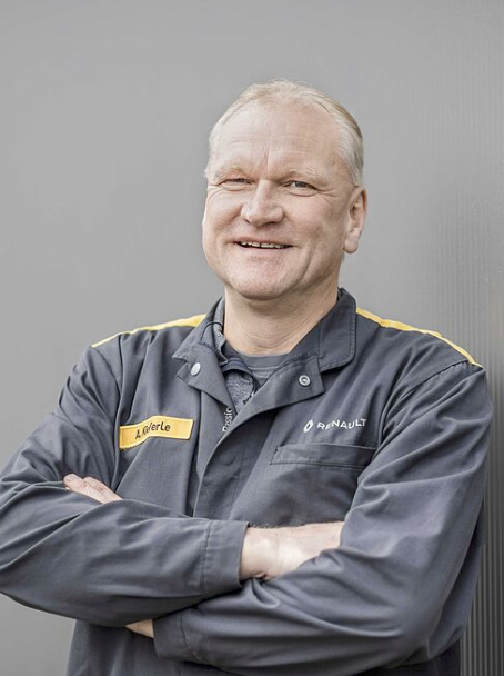 Mann in Arbeitskleidung mit verschränkten Armen.