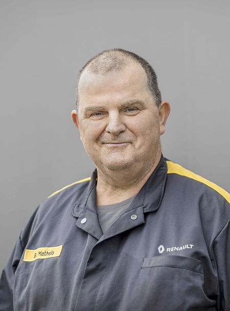 Mann in Arbeitskleidung vor grauem Hintergrund.