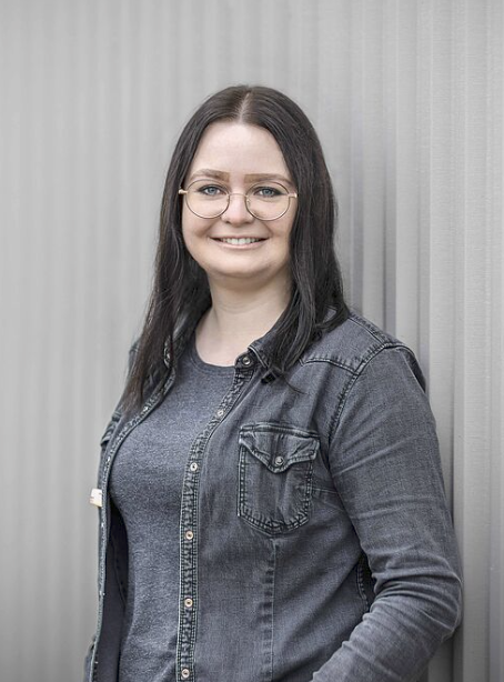 Frau in grauer Kleidung vor Wand