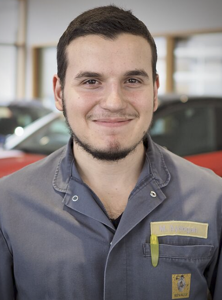 Mechaniker in Arbeitskleidung vor Autos