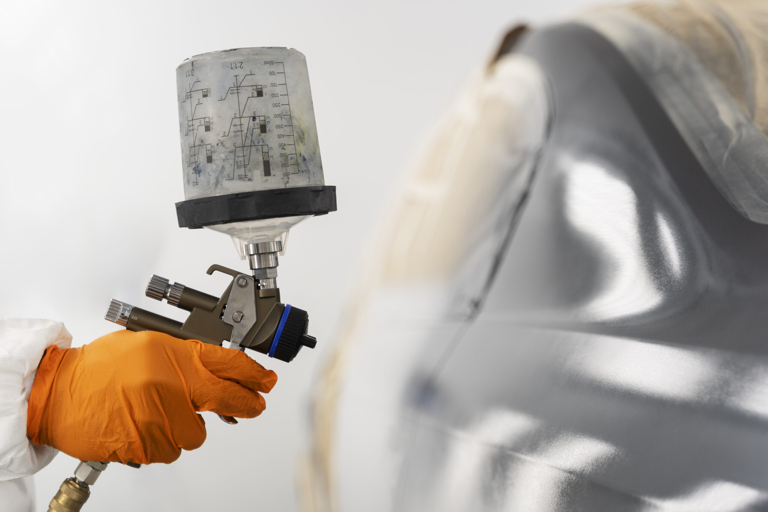 Mitarbeiter sprüht Farbe auf Auto